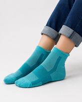 A close-up of a person's feet wearing teal blue quarter length socks with a textured knit pattern.
