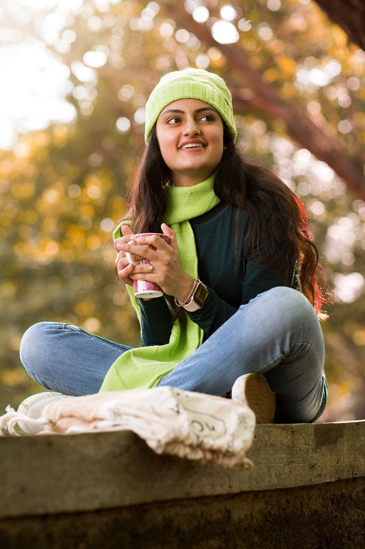 A woman, in cozy winter wear, enjoying a cup of coffee