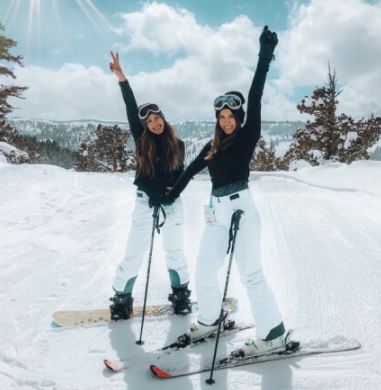 Two women smiling and enjoying the outdoors, dressed in colorful ski gear, ready for a day on the slopes.