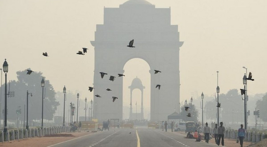 India Gate in Delhi on a winter day, enveloped in light fog, with people in warm clothing adding to the serene and tranquil atmosphere.