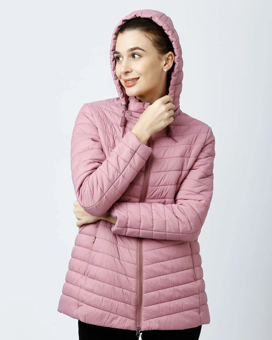 Woman wearing a light pink Kosha quilted winter jacket with hood, smiling confidently.