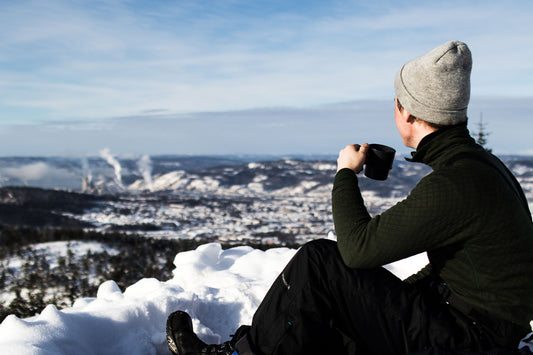 Photo by Sindre Fs of a man holding cup sitting on the snow