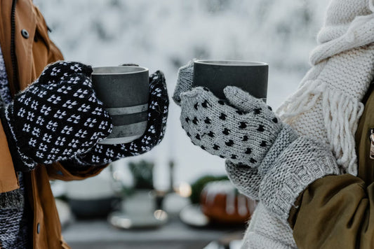 Two people sharing a warm cup of coffee, wrapped in the cozy comfort of Kosha’s winter layers.