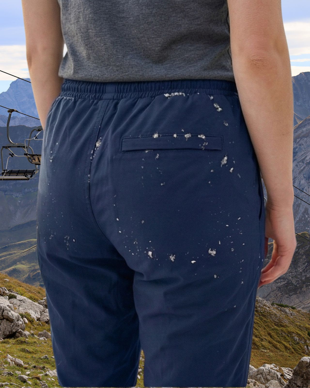 Person wearing navy blue waterproof pants with a mountainous landscape in the background