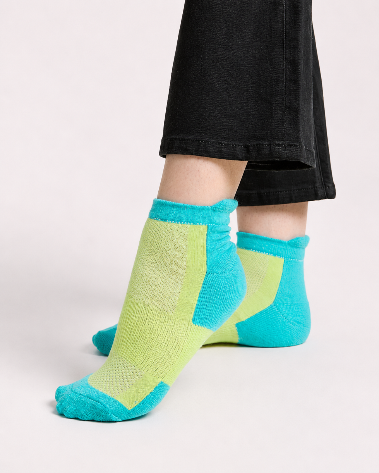 A person wearing bright neon green and quarter length technical socks, paired with black jeans.